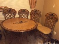 Full view of wood round kitchen table with four matching chairs against wall under window.