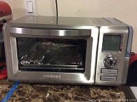 Front view of stainless steel Cuisinart toaster oven with digital display and control dial showing a food tray inside