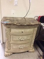 Front and top view of the ornate side table with faux marble top showing the carved details and three drawers.