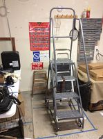 Whole ladder in an indoor workshop setting, surrounded by various shop tools and storage units.