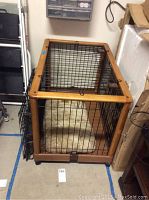 Large wood framed metal dog crate with plastic base and cushy pillow inside, viewed from the front.