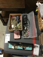 Overview photo showing assorted costume jewelry in various boxes and cases on a gray table.