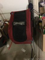 Front view of doggy bike attachment showing red fabric with black mesh area and metal frame underneath.