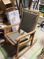 Full view of wooden rocking chair showing natural wood frame and woven seat and backrest.