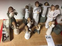 Full view showing a collection of ten Willow Tree figurines arranged, including angel figures with wire wings, people holding birds, and one small box with bird figurines.