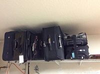 Five black suitcases on a shelf, showing the entire assortment and variety in size.