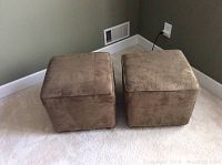 Two brown cloth ottomans photographed from the front, showing cube shape and fabric texture against a carpeted floor.
