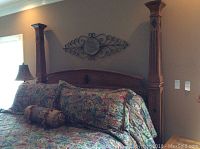 Front-left perspective of assembled bed frame with bedding (not included), showing left headboard post and curved headboard with inlay.