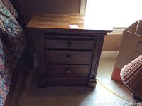 Front view of the wooden night stand showing three drawers.