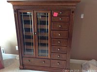 Full front view of brown wooden chest showing eight drawers and two glass-front doors