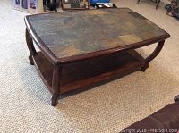 Full view of the rectangular brown coffee table with tiled top and wooden lower shelf on carpeted floor.