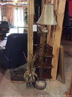 Photo showing the pear-shaped floor lamp next to the wood wall hanging shelf and faux plant with elephant base, an overview of grouping in room setting.