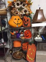Photo of display with large Halloween pumpkin decorations, fall wreath, and other table decorations on a metal bakers rack.