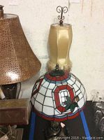 Photo showing stained glass shade lamp and tall gold fabric shade lamp side by side.