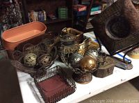 Photo showing various metal home decor items including iron baskets, metal planters, decorative spheres, napkin holder, and metal box on a table.