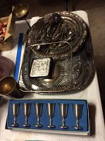 Photo of entire lot showing six pewter cordial cups in blue box, silver plated trays, wire basket, embossed box, and assorted serving utensils.