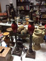 Two tall decorative lamps with red glass bodies on a table with other decor