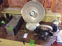 Craftsman circular saw, Presto HeatDish heater, metal live animal trap, 4-ton bottle jack, two oil cans on a wooden surface