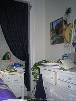 Photo of white antique dresser with decorative floral motifs and glass knob drawer pulls, placed in room corner near window