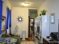 Living room showing assembled white modular entertainment wall unit with shelving, decorative items, and green plants on top.