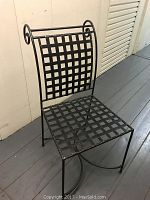 Front view of black wrought iron chair showing lattice seat and backrest