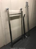 Photo of separated metal frame pieces for a double clothing rolling rack including wheels and bars