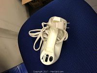 Electric hand mixer top view with power cord coiled on blue fabric chair