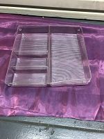Clear plastic flatware organizing tray showing front view with three smaller and one larger compartments, placed on purple cloth.