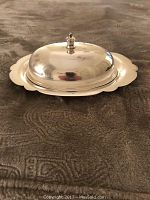 Silver plated covered butter dish with lid, showing reflective silver surface and scalloped edges on base.