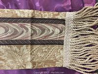 Close-up of the gold patterned fabric and thick twisted fringe.