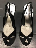 Pair of black Stuart Weitzman women's high heel shoes, size 7.5, showing top view with paper stuffing inside toe area.