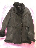 Dark brown shearling double breasted coat, front view showing buttons, collar, pockets, cuffs, and hem detail.