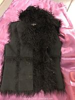 Front view of the black faux fur vest showing shaggy collar and trim with smooth panels.
