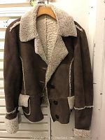 Front view of the brown shearling short jacket showing button closure and shearling trim.