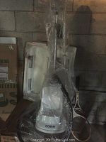 Full view of Conair fabric steamer showing base unit, metal pole, and attached black hose still in plastic wrapping