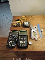 All items arranged on wooden surface including two calculators, two Walkman players with cords, Omron pedometer with strap and manual, and wristwatch.