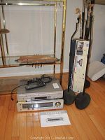 Photo of Sony SLV-D300P DVD/VHS combo player, Luxman R-406 receiver stacked, speaker stands, and Luxman receiver manual on floor.