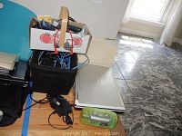 View showing closed Dell Inspiron 9300 laptop among miscellaneous items including cables, power supplies, and electronics in containers.