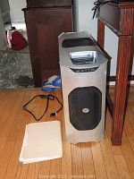 Full view of the silver gaming computer tower with mesh panels for airflow, power cord beside it.