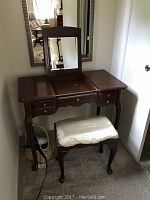 Front view of vintage vanity with closed mirror and cushioned bench underneath