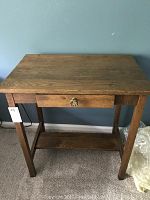 Front view of small oak vintage desk showing drawer and small shelf below.