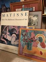 Framed Matisse poster from The Baltimore Museum of Art, a colorful still life print, and several smaller framed pieces in the background.