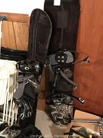 Two snowboards standing upright with bindings attached, one black with skull graphics (Fifty One Fifty Crux), the other black with white logos (Morrow 141).