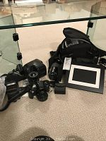 Minolta Maxxum TSi 35mm camera with 28-80mm lens attached, 70-210mm lens, camera carrying case, external flash, and framed digital photo frame arranged on carpet.