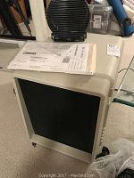 Front view of Friedrich electronic air cleaner with black grille and instruction manual on top