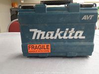 Closed blue Makita branded hard plastic carrying case with 'AVT' marking and a fragile handle with care sticker.