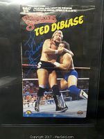 Full view of the autographed Ted DiBiase mini poster showing the wrestling action and autograph