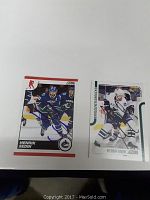 Two signed Henrik Sedin hockey cards side by side on white surface, one card has red border the other more white and green design