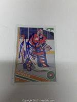 Photo of signed Patrick Roy hockey card in red and blue goalie uniform, with signature in blue ink.