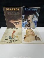 Four 1960's Playboy magazines laid out on black surface showing front covers.